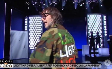 Fuori dal coro, Cruciani in giacca militare: la scritta sulla schiena, pugno a toghe e sinistra