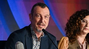 Amadeus, John Travolta e la pubblicità occulta alle scarpe? "Lo slogan solo un caso"