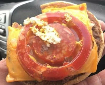 Mangia l'hamburger ma al posto del pomodoro c'è un coperchio di plastica